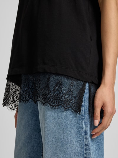 Frauenmodel trägt T-Shirt mit Spitze Modell 'SURE' von FREE/QUENT, Baumwoll-Elasthan-Mix, schwarzer Stoff, blaue Jeans, Nahaufnahme Oberkörper.