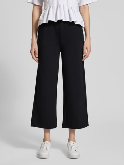 Kobiece modelka nosi czarne spodnie dresowe Wide Fit Sweatpants in verkürzter Passform Modell 'Banu' od Soyaconcept z elastyczna mieszanka materiałów z domieszką modalu, skrócony krój, elastyczny pas z tunel, detaliczny widok przodu całej sylwetki.