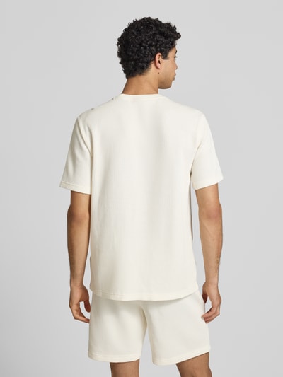 Männermodel trägt T-Shirt mit Strukturmuster und Label-Stitchings von CHAMPION aus Baumwoll-Mix, Regular-Fit, Rückenlänge 68 cm, Ganzkörperansicht Rückansicht.