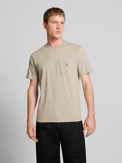 Männermodel trägt T-Shirt mit Label-Detail von Carhartt Work In Progress in Beige, reine Baumwolle, Regular Fit, Nahaufnahme Oberkörper.