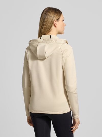 Frauenmodel trägt beigefarbene Softshell-Jacke mit Kapuze Modell 'RIDER' von PEAK PERFORMANCE, glatte Struktur, Ganzkörperansicht Rückansicht