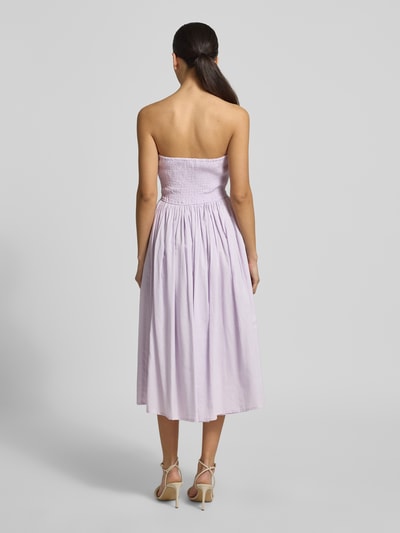 Frauenmodel trägt Cocktailkleid im Off-Shoulder-Look von LACE & BEADS aus Reine Baumwolle, A-Linie, Midikleid, Rückenlänge 96 cm, Brustweite 30 cm, sanfter Fliederton, Gelegte Falten, Ganzkörperansicht Rückansicht.