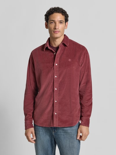 Männermodel trägt Regular Fit Freizeithemd mit Label-Stitching von MCNEAL aus rotem Cord mit Kentkragen, Ganzkörperansicht von vorne.