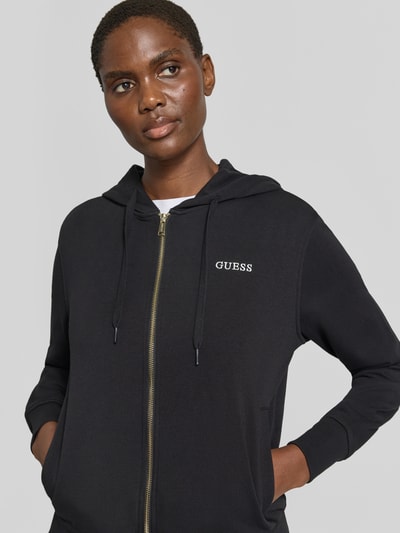 Vrouwenmodel draagt zwarte sweatjack met capuchon van katoenmix, regular fit, ritssluiting, labelstitching, Model 'SOFIA' van GUESS, Nahaufnahme Oberkörper