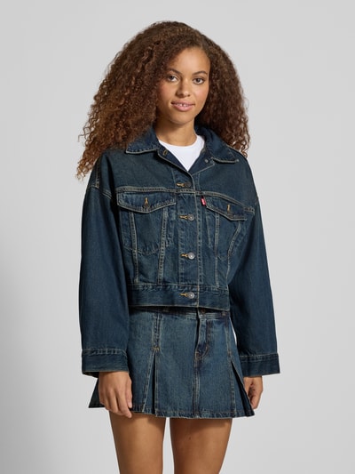 Frauenmodel trägt dunkle Jeansjacke mit Label-Detail Modell 'LOOSE CROP TRUCKER' von Levi's® 300, Kontrastnähte, Ganzkörperansicht von vorne.