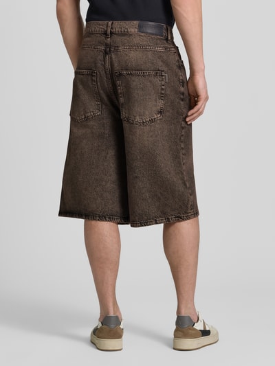 Männermodel trägt Jeansshorts mit Eingrifftaschen Modell 'Yuto Oak' von WOODBIRD, Reine Baumwolle, Relaxed-Fit, braun, Ganzkörperansicht Rückansicht.