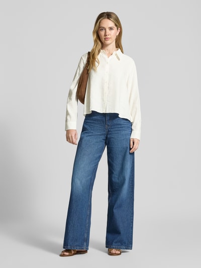 Vrouwenmodel draagt Relaxed fit Bluse aus Modal-Mix Modell 'Flowy' van OPUS in crème met lange mouwen en hemdblousekraag, voorkant volledig zichtbaar, relaxed fit, knoopsluiting, ruglengte 55 cm, mouwlengte 60 cm, Ganzkörperansicht von vorne.