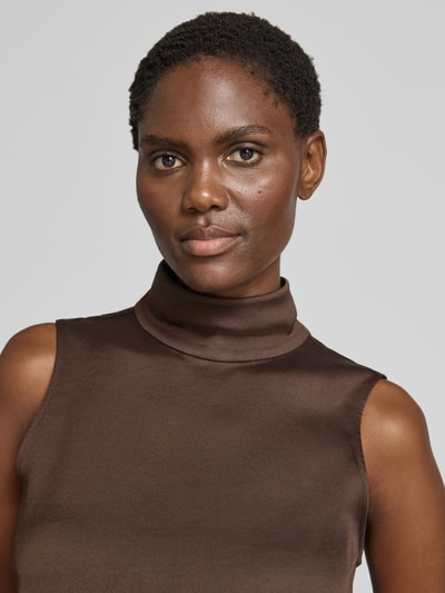 Frauenmodel trägt Blusentop mit Stretch-Anteil von DRYKORN aus braunem Satin, Rollkragen, ärmellos, Regular Fit, Nahaufnahme Oberkörper.