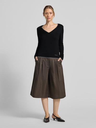 Frauenmodel trägt Slim Fit Longsleeve aus reine Viskose Modell 'Maglia Chiusa' von Liu Jo White in Schwarz mit V-Ausschnitt, Ganzkörperansicht von vorne.