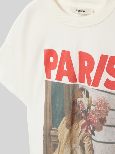 Mädchen trägt T-Shirt aus reiner Baumwolle von Garcia, weiß mit Label-Print, gerader Schnitt, Rundhalsausschnitt, Nahaufnahme Oberkörper.