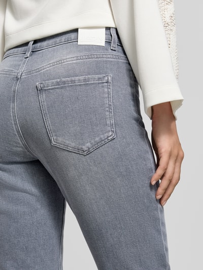 Frauenmodel trägt High Waist Slim Fit Jeans mit Label-Patch von MARC CAIN in Light Wash Denim, sichtbare Nähte und 5-Pocket-Design, Nahaufnahme Rückansicht.
