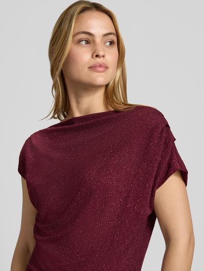 Vrouwenmodel draagt blouse met One-shoulder band van Rinascimento in bordeauxrood met glanzende structuur, materiaalmix met stretch, getailleerde pasvorm, geplooide details, ruglengte bij maat S 54 cm, close-up bovenlichaam.