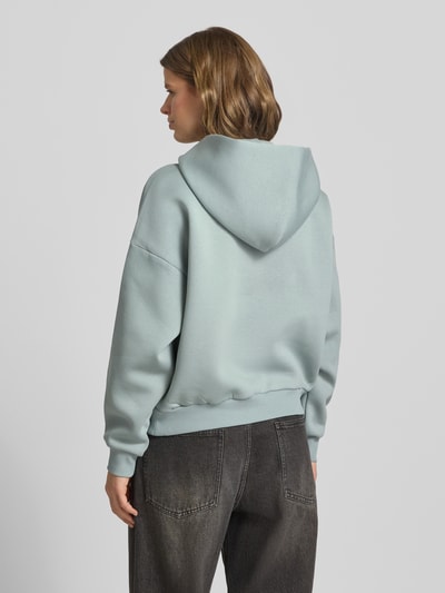 Frauenmodel trägt Hoodie mit Logo und Känguru-Tasche von Review, Damen, Baumwoll-Mix, Relaxed-Fit, Logo, Känguru-Tasche, Ganzkörperansicht Rückansicht.