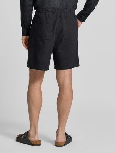 Männermodel trägt Leinenshorts mit elastischem Bund von GAP in Schwarz, Loose-Fit, Gesäßtaschen, Leinen-Baumwoll-Anteil, Ganzkörperansicht Rückansicht.