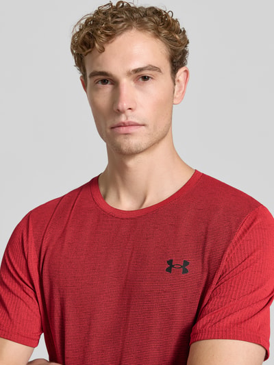 Männermodel trägt Regular Fit Sport-T-Shirt mit Logo-Print von Under Armour, rotes Feinstrickmaterial mit schwarzem Logo, Nahaufnahme Oberkörper, Herren Sport-T-Shirt von Under Armour.