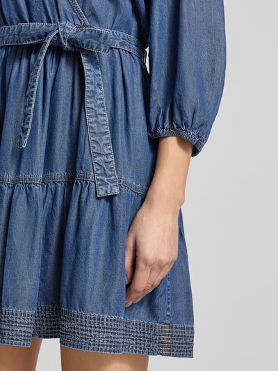 Kobiece modelka nosi tailliertes Freizeitkleid aus Lyocell Modell 'C_DARDY' od BOSS Orange w stylu jeansowym, z balonowymi rękawami i elastycznym paskiem, kontrastowe szwy, mini długość, detaliczne zbliżenie dolnej części sukienki, detaliczne ujęcie ręki, Nahaufnahme dolnej części sukienki.