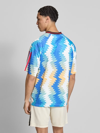 Männermodel trägt Regular Fit T-Shirt mit Allover-Muster von adidas Sportswear, farbenfroh, Optik:Allover-Muster, Ganzkörperansicht Rückansicht.