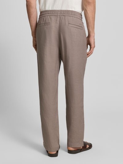 Männermodel trägt Straight Fit Schmale Hose aus Leinen-Lyocell-Mix Modell 'CINO' von HUGO in Taupe, elastischer Bund, Rückansicht Ganzkörperansicht.