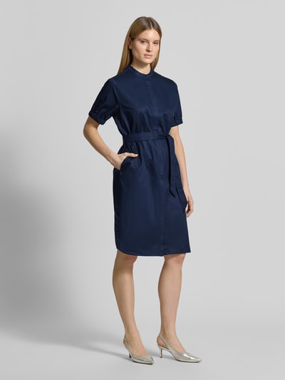 Modelka kobieca nosi Regular Fit Kleid mit Stehkragen von Fynch-Hatton, ciemnoniebieski, czysta bawełna, krój regular fit, stójka, taliowany, krótkie rękawy z elastycznymi mankietami, odpinany pasek w talii, pełna listwa guzikowa, kieszenie, długość tyłu w rozmiarze 36: 105 cm, szerokość w rozmiarze 36: 59 cm, długość rękawa w rozmiarze 36: 27 cm, widok całej sylwetki z przodu.