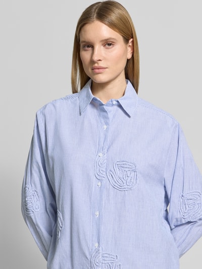 Frauenmodel trägt Relaxed Fit Bluse mit Streifenmuster Modell 'Dalma Dori' von Neo Noir aus reiner Baumwolle mit floralen Applikationen, Nahaufnahme Oberkörper.