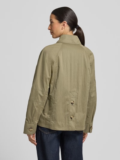 Frauenmodel trägt Jacke mit seitlichen Eingrifftaschen und Kentkragen von Fuchs Schmitt, prosty krój, kołnierzyk typu kent, listwa guzikowa, raglanowe rękawy, wpuszczane kieszenie, długość tyłu w rozmiarze 36: 64 cm, szerokość ramion w rozmiarze 36: 38 cm, szerokość klatki piersiowej w rozmiarze 36: 51 cm, długość rękawów w rozmiarze 36: 44 cm, kolor jasny oliwkowy, tekstura gładka, Ganzkörperansicht Rückansicht