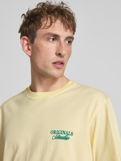 Männermodel trägt T-Shirt mit Label-Print von Jack & Jones in Hellgelb, Reine Baumwolle, Relaxed-Fit, Rundhalsausschnitt, Nahaufnahme Oberkörper.