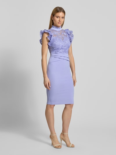 Modelka nosi Slim Fit Midikleid mit Spitzenbesatz von Lipsy z elastycznej mieszanki materiałów, krój slim fit, obszycie koronką, stójka z obszyciem falbanami, krótkie rękawy z falbanami, zamek błyskawiczny, półprzezroczysty materiał, plisy, rozporek, długość tyłu w rozmiarze 36: 108 cm, szerokość w rozmiarze 36: 38 cm, jasnofioletowe odcienie, prosty fason, gładka tekstura, widok całej sylwetki z przodu.