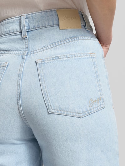 Frauenmodel trägt Straight Fit 7/8 Jeans von BOSS Orange in heller Denim-Optik mit Logo-Stitching, reine Baumwolle, Detailaufnahme Rückansicht.