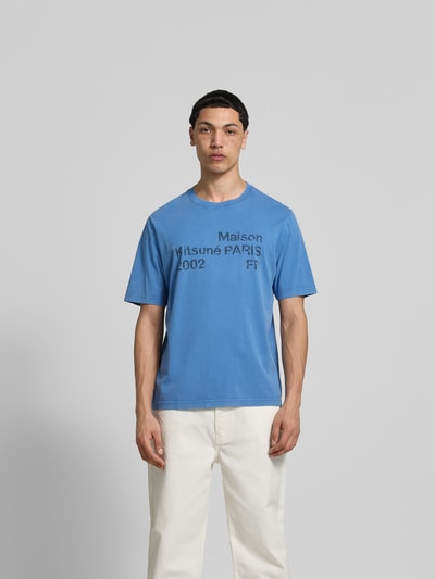 Männermodel trägt Relaxed Fit T-Shirt mit Logo-Print von MAISON KITSUNÉ aus reiner Baumwolle in Blau, Rundhalsausschnitt, Kurzärmelig, Rückenlänge 69 cm bei Größe M, Ganzkörperansicht von vorne.