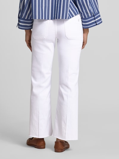 Frauenmodel trägt Relaxed Fit Jeans aus Baumwoll-Mix Modell 'TESS' von Cambio in weißer Denim-Optik mit Fransen Beinabschluss, Gesäßtaschen, Logo-Applikation, Label-Patch, Gürtelschlaufen, Knopf und verdecktem Reißverschluss, Twill-Materialverarbeitung, Ankle-Länge, Ganzkörperansicht Rückansicht.