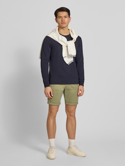 Mannelijk model draagt Regular Fit Shorts met steekzakken model 'BOWIE' van Jack & Jones, mix van katoen en elastaan, regular fit, omslag, bandwijdte maat M 43 cm, binnenbeenlengte maat M 26 cm, geheel in lichtgroen, gladde textuur, casual uitstraling, frontale gehele lichaamsweergave.
