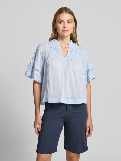 Frauenmodel trägt Bluse mit Häkelspitze Modell 'Siama' von Neo Noir, hellblaue Loose-Fit-Bluse mit Serafino-Kragen, 1/2-Arm, Ganzkörperansicht von vorne. Rückenlänge bei Größe 36: 58 cm, Ärmellänge bei Größe 36: 30 cm.