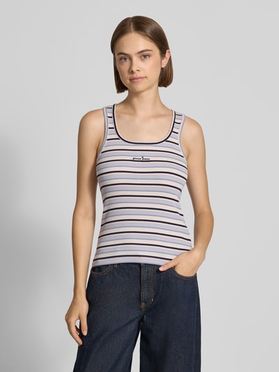 Frauenmodel trägt Slim Fit Top aus Baumwoll-Mix mit Logo-Stitching von GUESS, schmale Streifen in Weiß, Blau und Beige, Rundhalsausschnitt, Ganzkörperansicht von vorne, Damen Top von GUESS Jeans, elastischer Baumwoll-Mix, Rückenlänge 52 cm bei Größe S.