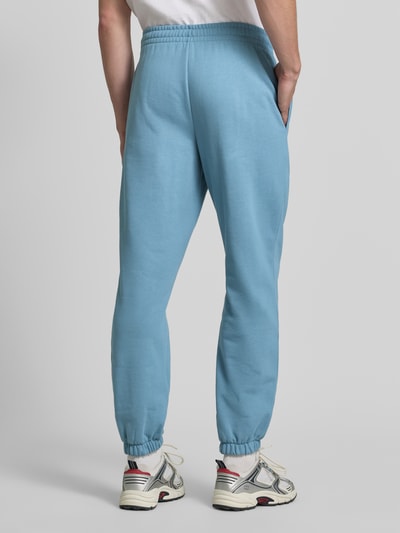 Männermodel trägt Regular Fit Sweathose aus Baumwoll-Mix von Lacoste in Hellblau mit elastischen Bündchen, Ganzkörperansicht Rückansicht.