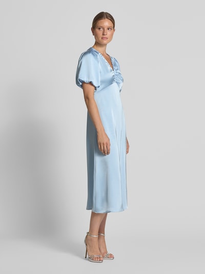 Frauenmodel trägt Midikleid aus Satin Modell 'Illana' von Neo Noir in Hellblau, tailliert, kurzärmelig, V-Ausschnitt, Ganzkörperansicht von vorne.