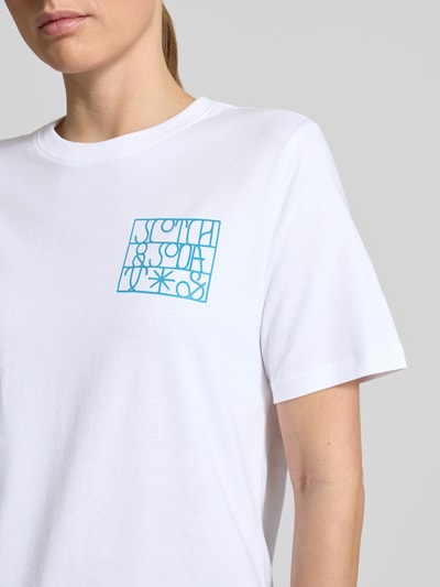 Vrouwenmodel draagt Regular Fit T-shirt met logoprint van Scotch & Soda, puur katoen, ronde hals, ruglengte maat S 61 cm, close-up bovenlichaam.