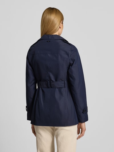 Frauenmodel trägt Regular Fit Trenchcoat aus Baumwoll-Mix von s.Oliver RED LABEL, jednokolorowy granatowy, splot twill, hydrofobowy, aplikacja z metką, pasek w talii, długi rękaw, pagony, detal na plecach, kieszeń wewnętrzna, wpuszczane kieszenie, widok całej sylwetki z tyłu