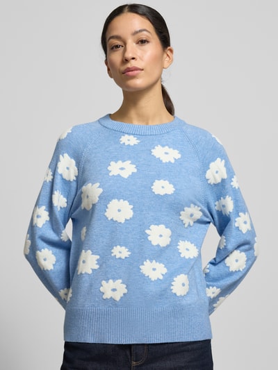 Frauenmodel trägt Strickpullover mit gerippten Abschlüssen Modell 'Alpie' von FREE/QUENT, blauer Viskose-Mix mit weißen Blumen, Nahaufnahme Oberkörper.