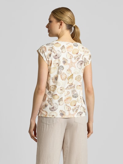 Kobiece model prezentuje Regular Fit T-Shirt mit Allover-Motiv-Print od Marc Cain, elastyczna mieszanka bawełny, okrągły dekolt, długość pleców w rozmiarze 36: 58 cm, beżowe i pastelowe odcienie, wzór muszli, tekstura gładka, widok całej sylwetki od tyłu.