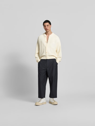Männermodel trägt Strickjacke mit floralem Stitching von MAISON KITSUNÉ, Baumwoll-Mix, Regular-Fit, helle Farbe, Knopfleiste, elastische Abschlüsse, Ganzkörperansicht von vorne.