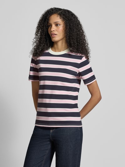 Frauenmodel trägt T-Shirt aus reiner Baumwolle von Jake*s Casual mit geradem Schnitt, Rundhalsausschnitt, kurzärmelig, Rückenlänge 58 cm, gestreiftes Design in Rosa, Weiß und Dunkelblau, Ganzkörperansicht von vorne.