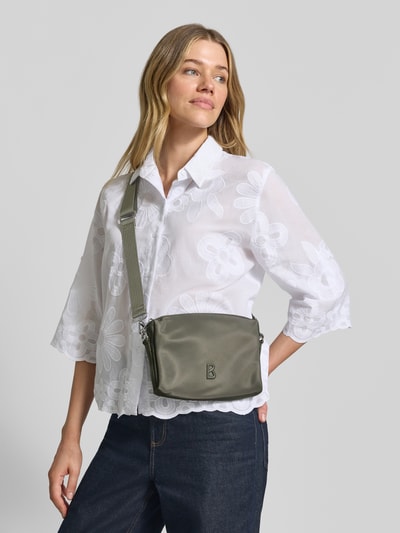 Kobieta modelka nosi Handtasche mit Label-Detail und Schulterriemen od BOGNER, szaro-zielony kolor, materiał gładki, pasek na ramię, Szerokość w rozmiarze 1: 23 cm, długość: 15 cm, głębokość: 4 cm, długość paska: 102 cm, główny zamek, wewnętrzna kieszeń na zamek, widok całego ciała z przodu