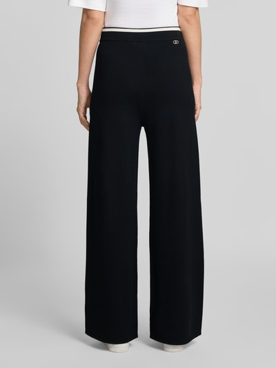 Vrouwenmodel draagt zwarte wide fit Sweatpants met contrasterende tailleband en siernaad, 'MAGLIA LUNGO' van Liu Jo Sport, viscosemix, zicht van achteren.