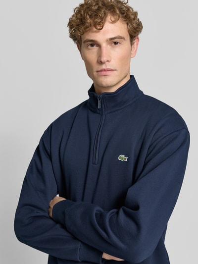 Männermodel trägt dunkelblauen Regular Fit Troyer aus Baumwoll-Mix von Lacoste, dezentes Logo, Nahaufnahme Oberkörper, Herren Troyer von Lacoste.