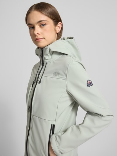 Frauenmodel trägt Trekker Jacke mit Kapuze und Label-Patch von Superdry in hellem Grau, glatte Textur, dezente Logo-Stitchings, Material-Mix mit Stretch, seitliche Reißverschlusstaschen, Stehkragen, Detailaufnahme Oberkörper schräg vorne.
