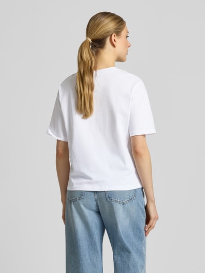 Frauenmodel trägt T-Shirt mit Motiv-Print Modell 'Beach Dogs' von monari aus weißer Baumwolle im Regular Fit, Ganzkörperansicht Rückansicht.