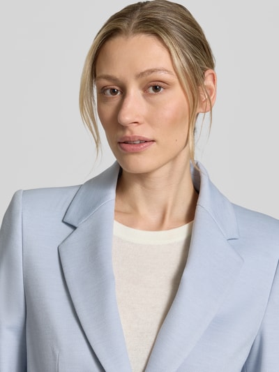 Modelka kobieca nosi Slim Fit Blazer mit Pattentaschen Modell 'BUNDREY' od Drykorn w jasnoniebieskim kolorze, faktura gładka, krój slim fit, z klapami, zapięcie na guzik, szerokość w rozmiarze 36: 43 cm, długość pleców w rozmiarze 36: 62 cm, długość rękawa w rozmiarze 36: 62 cm, z patkami na kieszeniach, zbliżenie na górną część ciała.