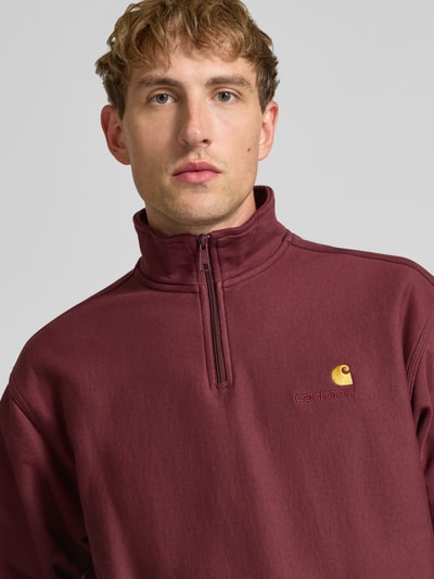 Männermodel trägt Relaxed Fit Sweatshirt aus elastischem Material-Mix von Carhartt Work In Progress, Troyer-Kragen, Label-Detail, Nahaufnahme Oberkörper.