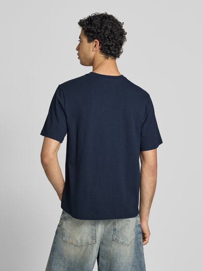 Männermodel trägt T-Shirt mit Label-Patch und Rundhalsausschnitt von REVIEW, reine Baumwolle, Boxy Fit, Rückansicht Ganzkörperansicht