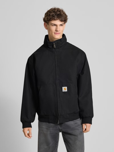 Männermodel trägt Jacke mit Zweiwege-Reißverschluss Modell 'Ravon' von Carhartt Work In Progress, Schwarz, Baumwolle, Ganzkörperansicht von vorne.